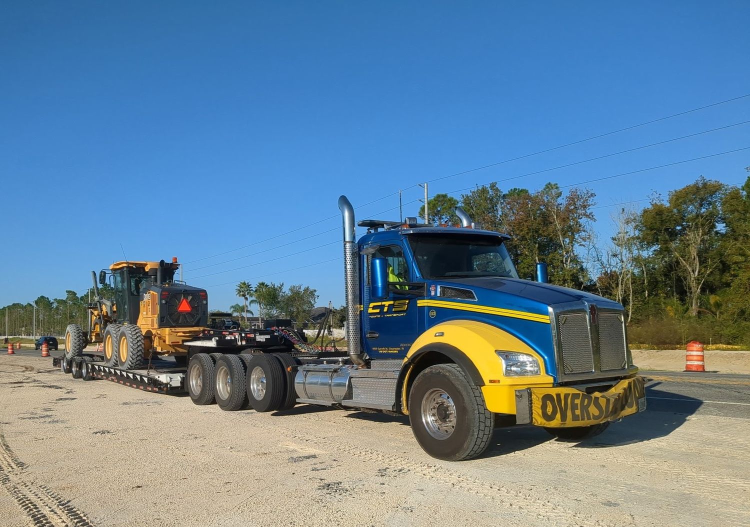 CTS lowboy transporting a John Deere motor grader
