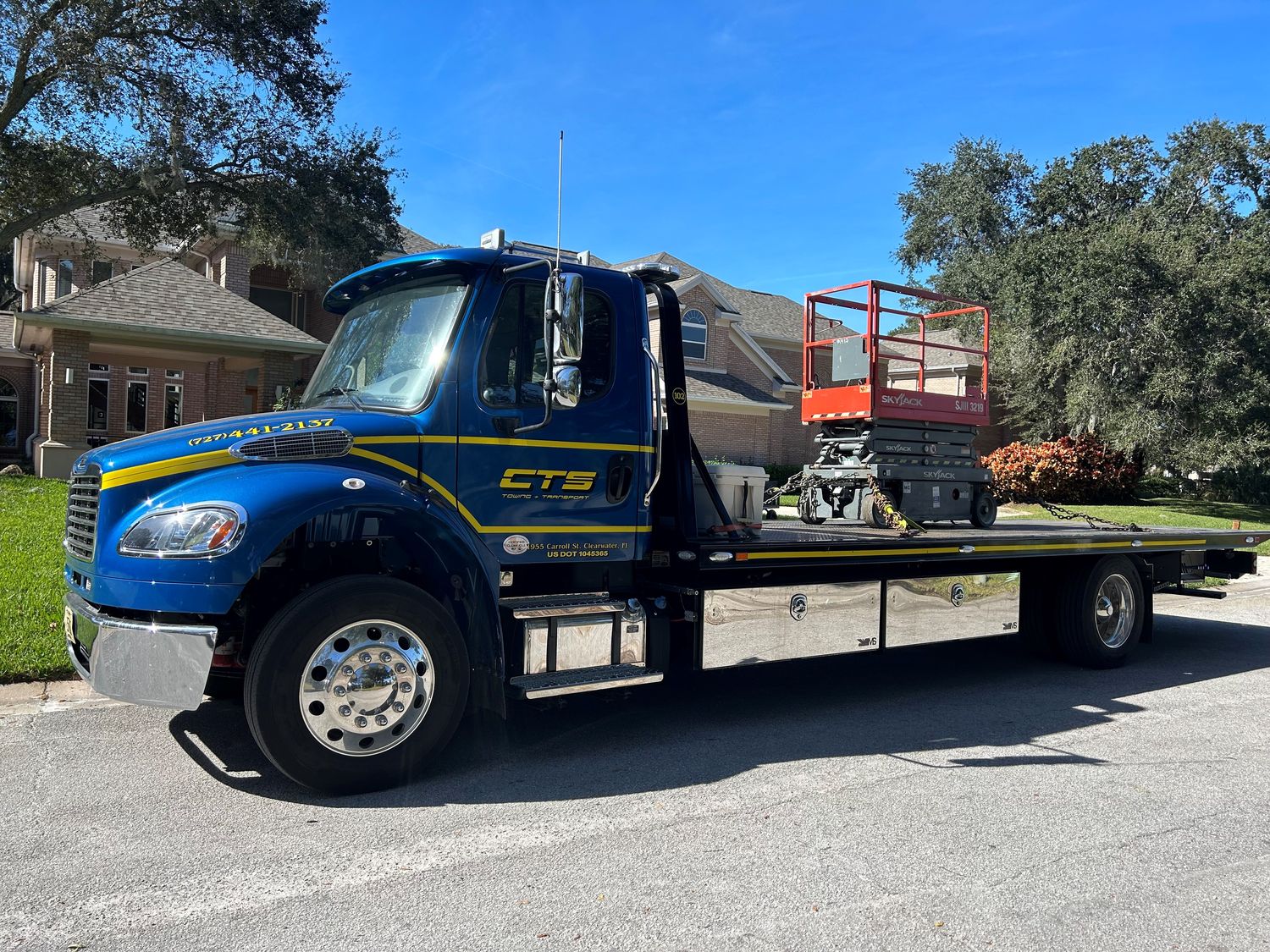 CTS industrial rollback hauling a scissor lift